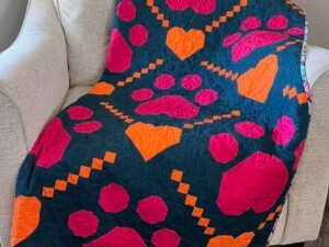 Paw Prints on My Heart quilt draped over sofa chair.
