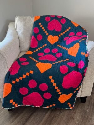 Paw Prints on My Heart quilt draped over sofa chair.